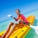 A young girl smiles while paddling a kayak in shallow waters